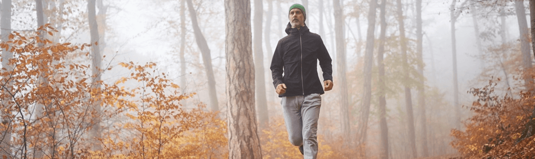 Man running outside through trees on a foggy day in the fall
