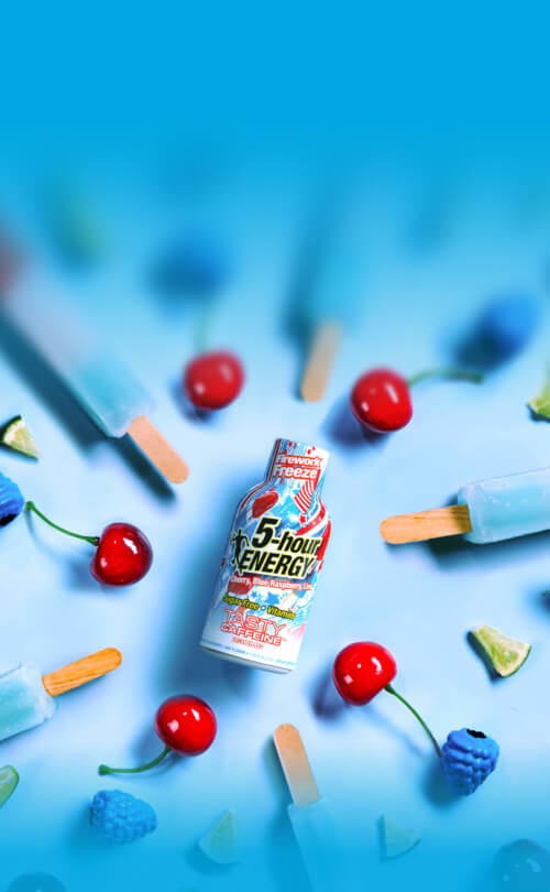 5-hour Energy drink bottle surrounded by cherries and popsicles on a blue background