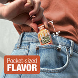 A close-up lifestyle shot of a person's hand holding a miniature orange bottle of 'Pumpkin Spice 5-hour Energy' pocket-sized flavor between their jeans. The image includes text overlays showing the bottle's height as 3.5 inches