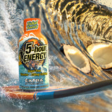 A bottle of Tidal Twist 5-hour Energy Extra Strength placed on a surfboard in ocean water, with a large wave and coconut shells in the background.