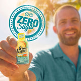 A man in a teal shirt holds up a small bottle of 5-hour Energy Zero Sugar drink mix, with a large teal 'Zero Sugar' graphic overlay behind him on a bright outdoor background.