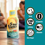 A bottle of 5-hour Energy Tropical Burst caffeine drink is shown on a table with a blurred indoor background, alongside a teal panel with feature icons for Tasty, 230 mg Caffeine, 0 Calories, Vitamins, and Zero Sugar.