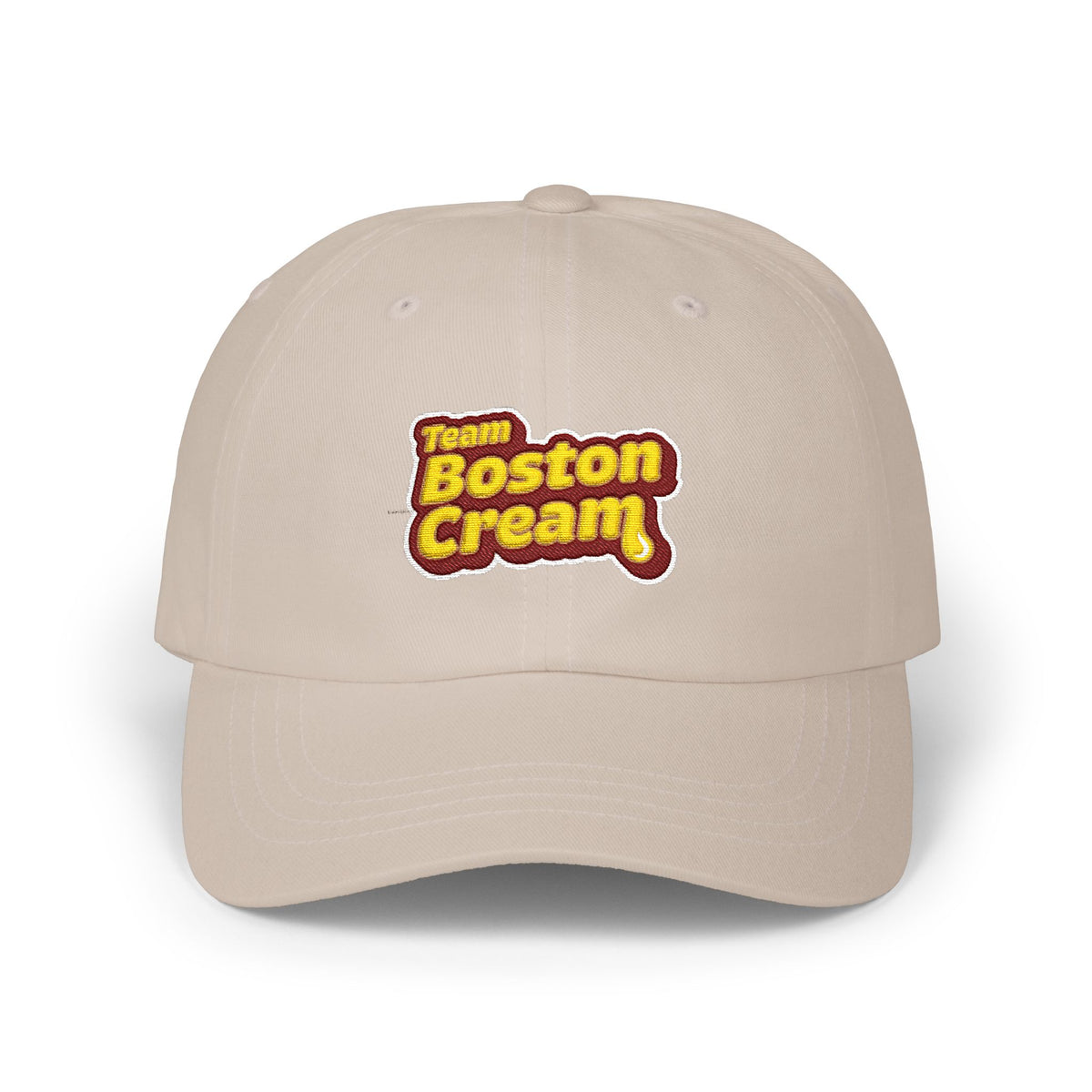 A beige baseball cap featuring a 'Team Boston Cream' graphic on the front, set against a plain white background.