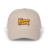 A beige baseball cap featuring a 'Team Boston Cream' graphic on the front, set against a plain white background.