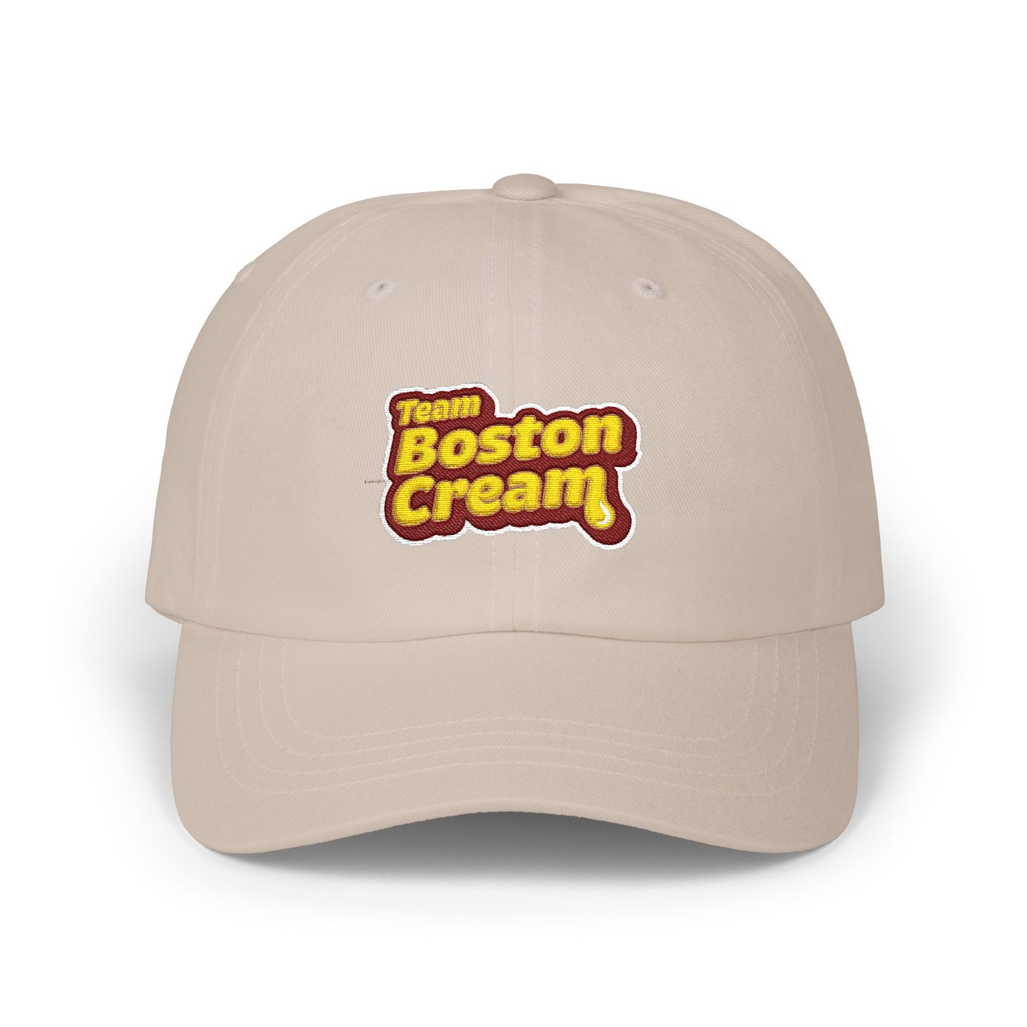 A beige baseball cap featuring a 'Team Boston Cream' graphic on the front, set against a plain white background.